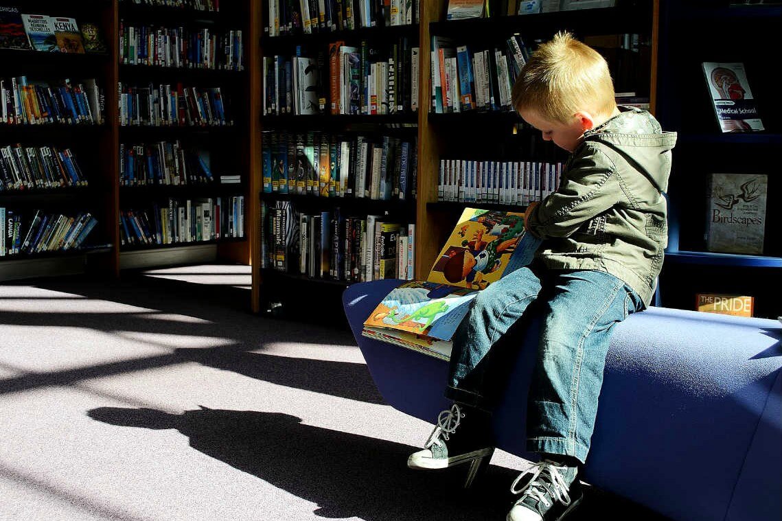 Niño leyendo en una biblioteca pública, imagen del acceso a la educación y el bienestar social